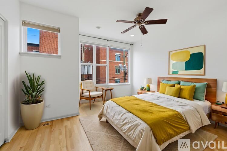 A bedroom with a bed, a chair, and a potted plant.