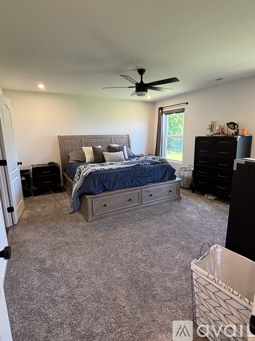 A bedroom with a bed, dresser, and ceiling fan.