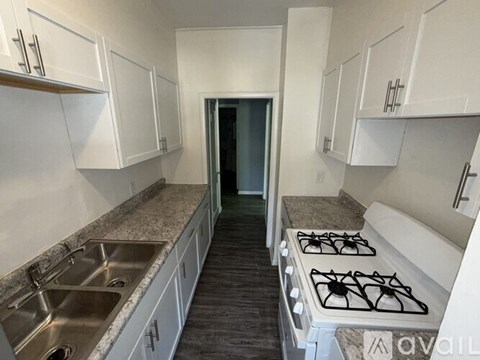 A kitchen with white cabinets and a stove top oven.