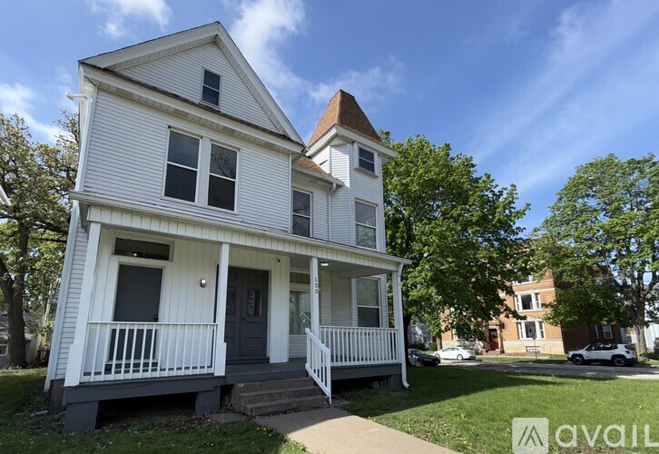 A two-story house with a white exterior and a balcony on the second floor.