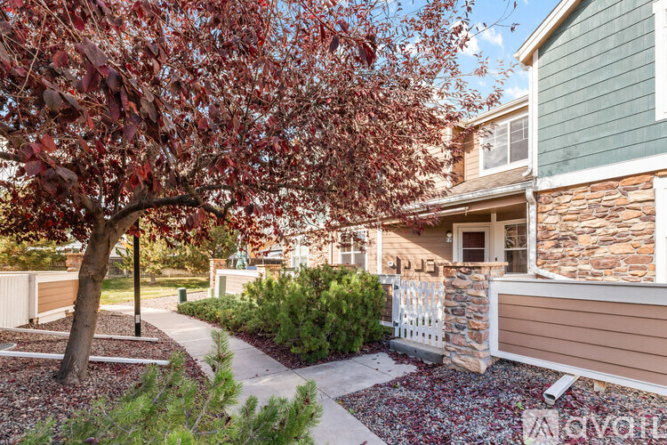 A tree with red leaves is in front of a house.