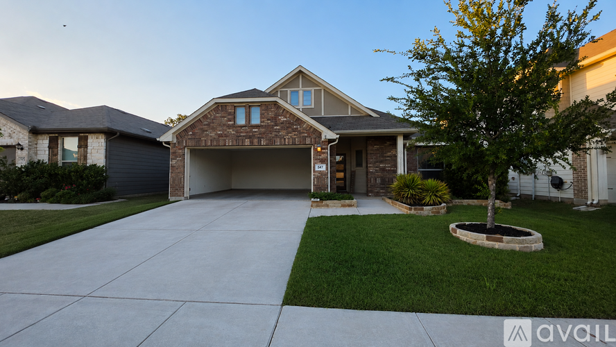 A house with a driveway and a tree in front.