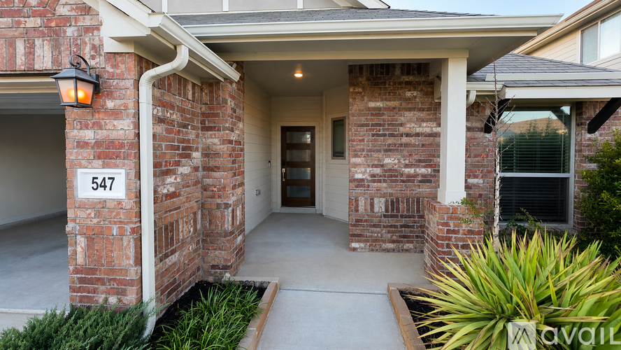 A house numbered 547 with a brick wall and a white door.