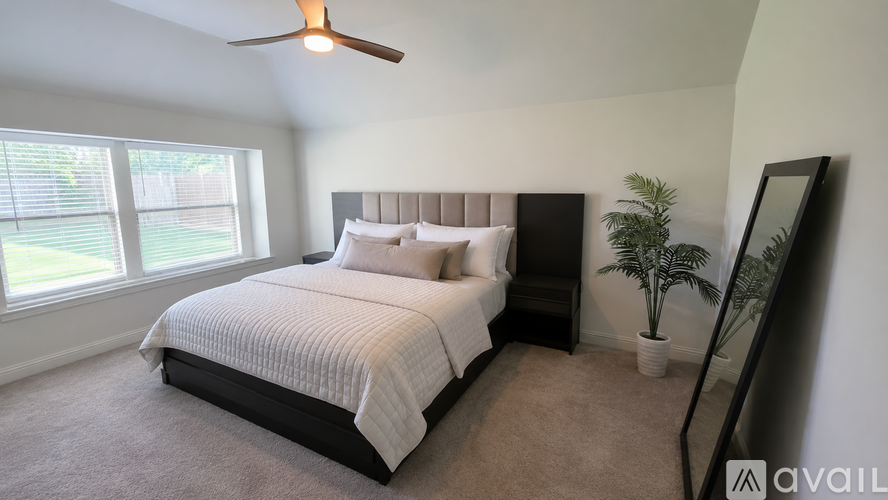 A bedroom with a large bed and a ceiling fan.