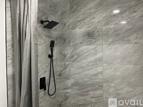 A shower head and hose are mounted on a marble wall.