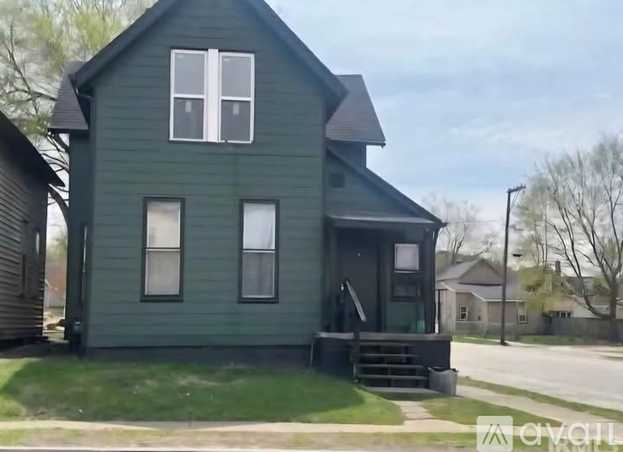 A green house with a white window is for sale.