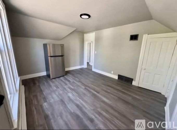 A room with a refrigerator and a door on the right side.