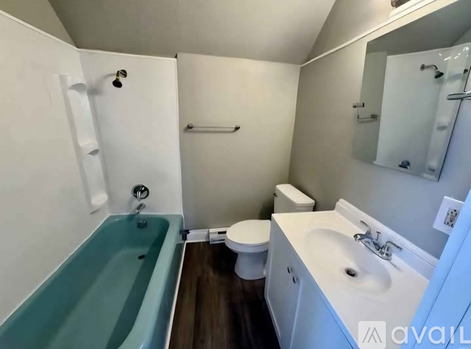 A bathroom with a blue bathtub, white sink, and toilet.