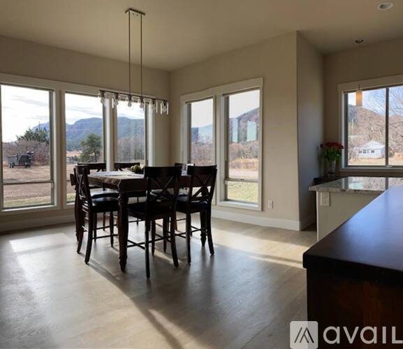 A dining room with a table and chairs and a view of the outdoors.