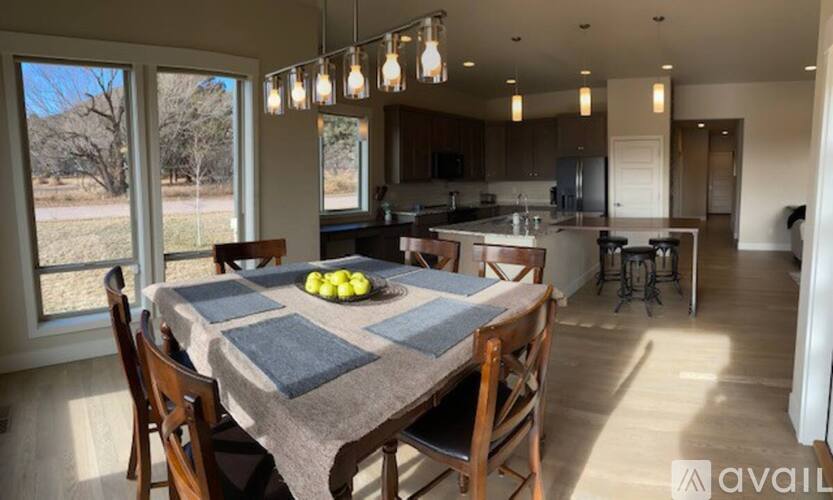 A dining room with a table set for four and a kitchen in the background.