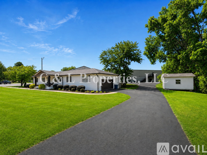 A building with the text "& Sons Properties, LTD" on it is surrounded by greenery and a paved path leading up to it.