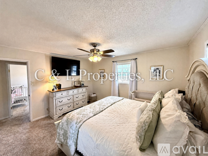 A bedroom with a large bed, a dresser, and a ceiling fan.