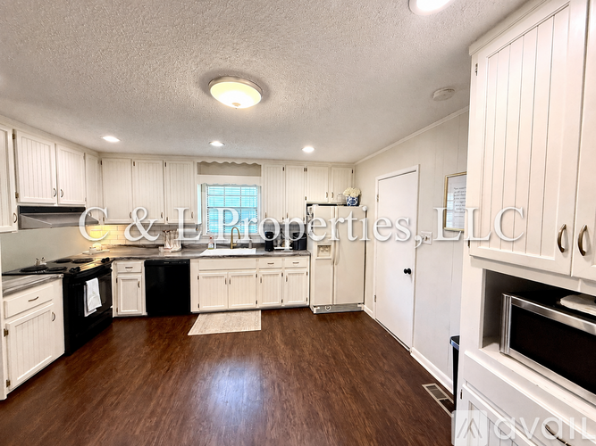 A kitchen with white cabinets and a wooden floor.