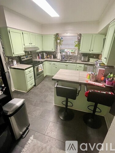 A kitchen with green cabinets and a table with two stools.