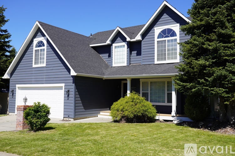 A blue house with a white garage door and a white window.