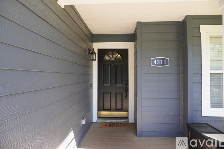 A black door with a gold handle is on the front of a house.