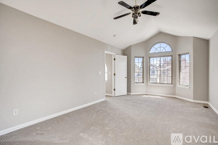 A spacious room with a ceiling fan and large windows.