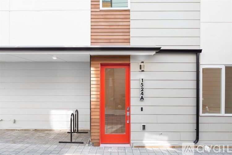 A modern house with a red door and a black pipe on the side.