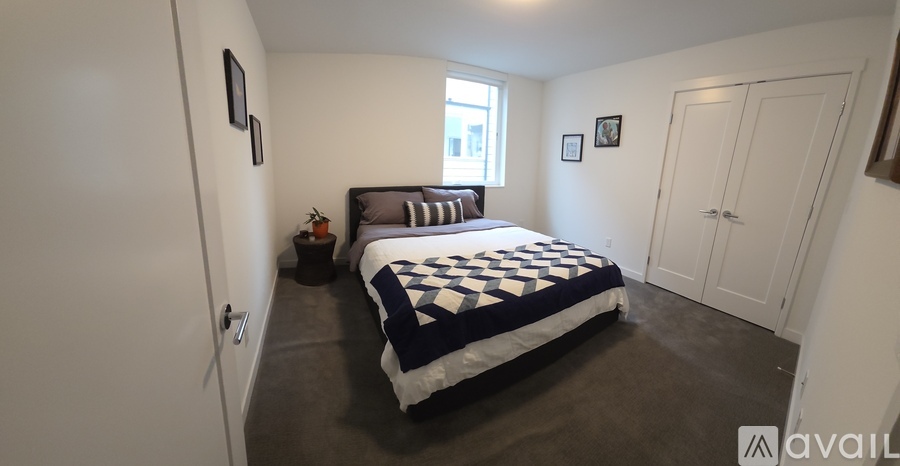 A bedroom with a bed, a window, and two pictures on the wall.