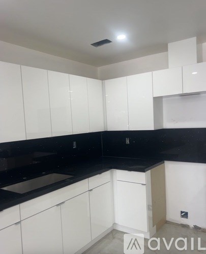 A kitchen with white cabinets and black countertops.