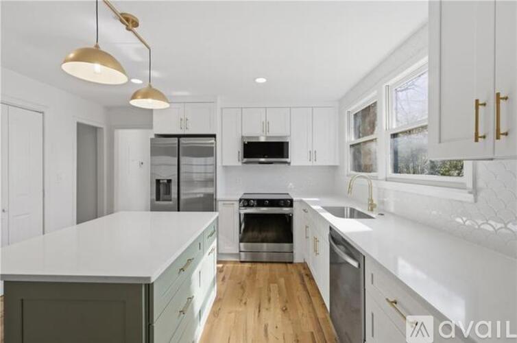 A modern kitchen with a white countertop and stainless steel appliances.