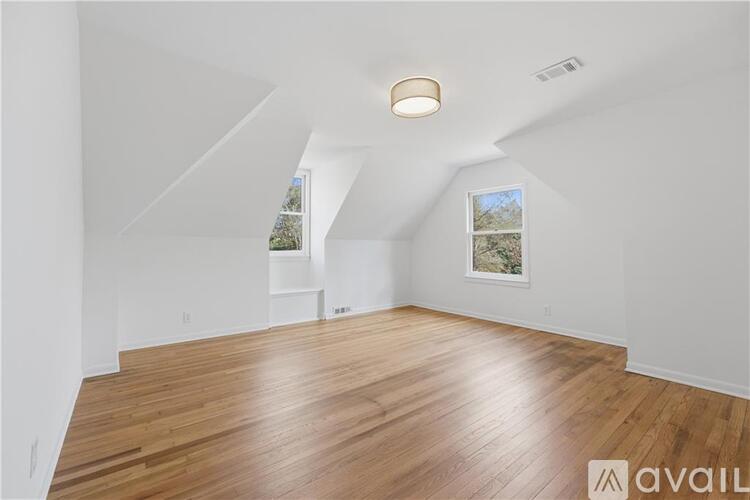 A spacious room with wooden flooring and white walls.