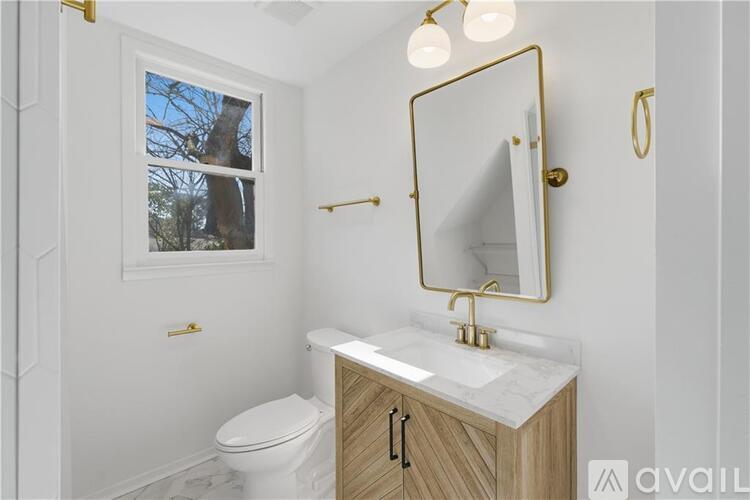 A bathroom with a toilet, sink, and a window.
