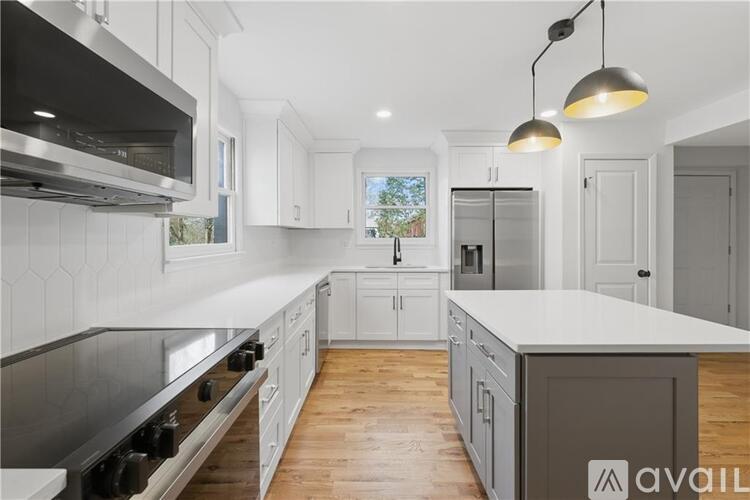 A modern kitchen with white cabinets and a wooden floor.