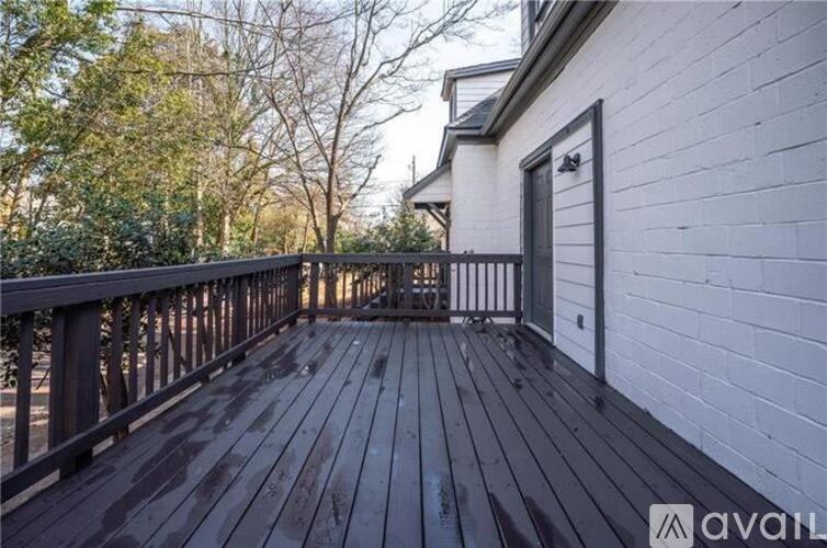 A wooden deck with a railing and a white building in the background.