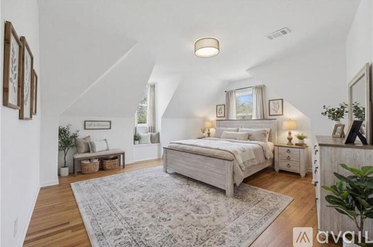 A bedroom with a large bed and a bench under a window.