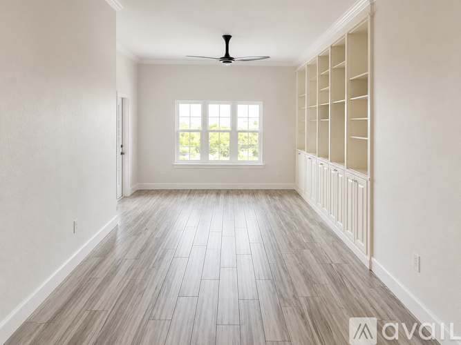 A spacious room with a ceiling fan and a window with blinds.