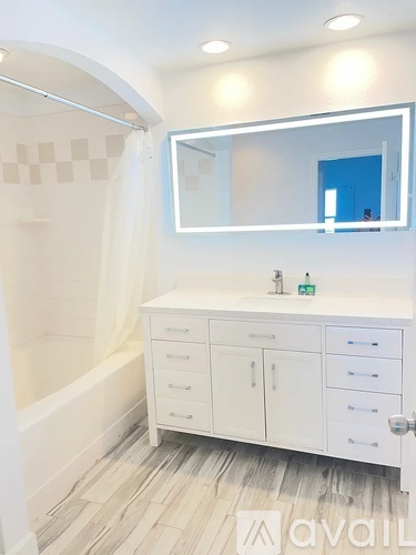 A bathroom with a white cabinet and a mirror above it.