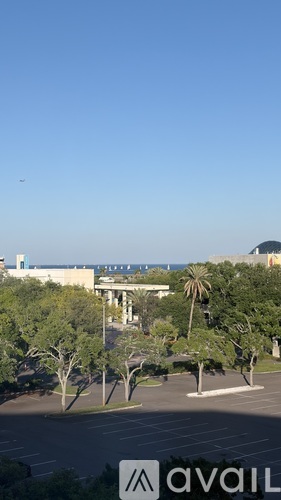 A view of a parking lot with trees and a building in the distance.