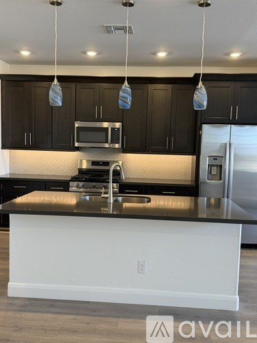 A kitchen with a white island and black cabinets.