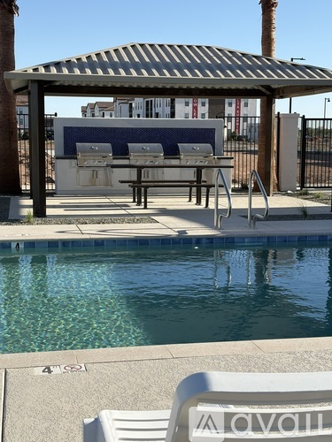 A pool with a white sunshade and a white chair with the word Avon on it.