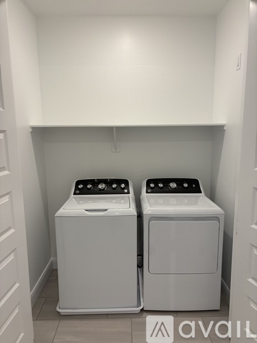 Two white front loading washing machines in a laundry room.