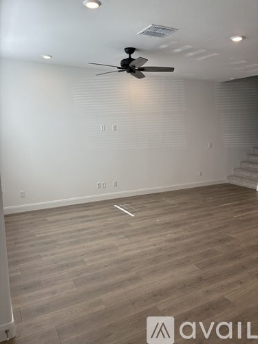 A room with a ceiling fan and wooden flooring.