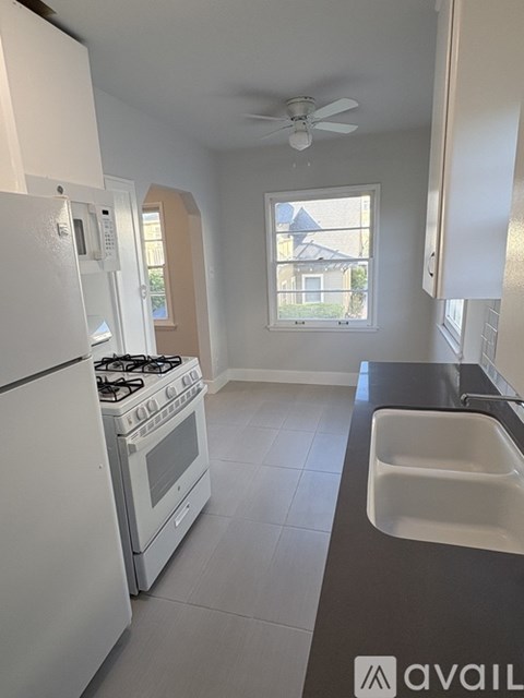 A kitchen with a white fridge, stove, and a window.
