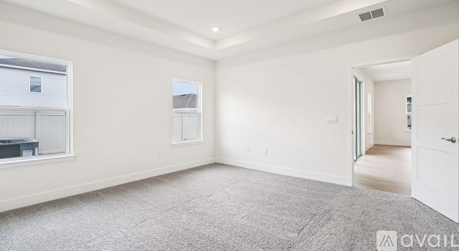 A spacious empty room with a carpeted floor and white walls.