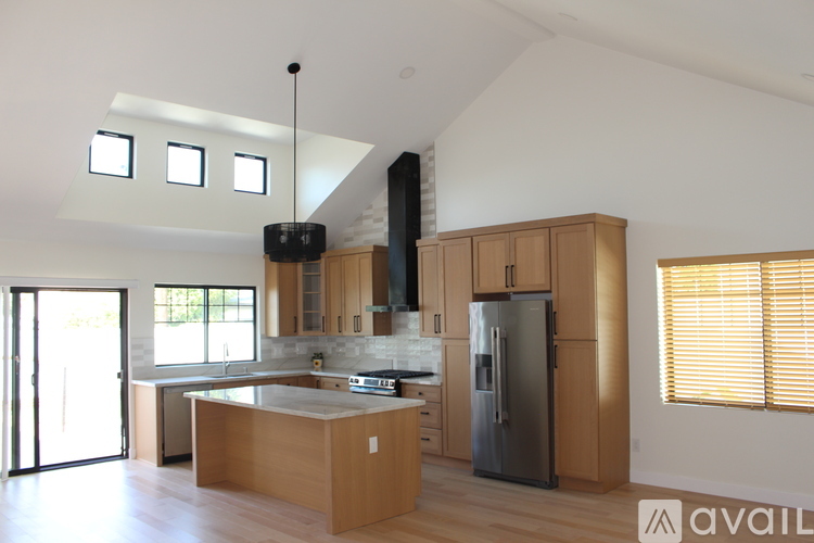 A kitchen with wooden cabinets and a black refrigerator.