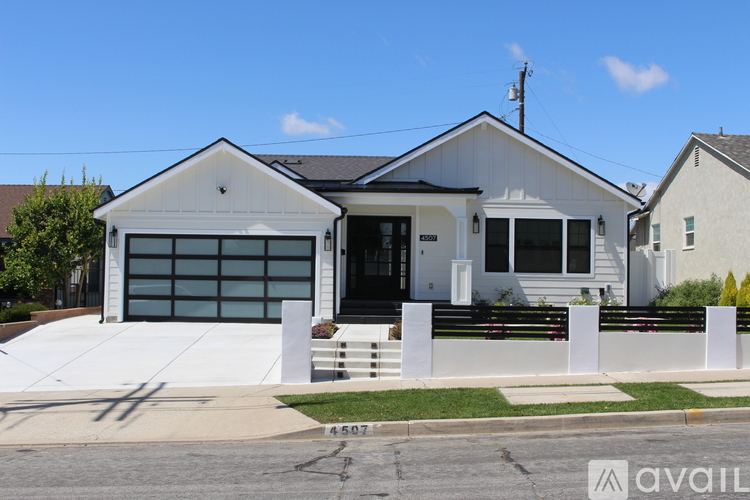 A white house with a black garage door is for sale.
