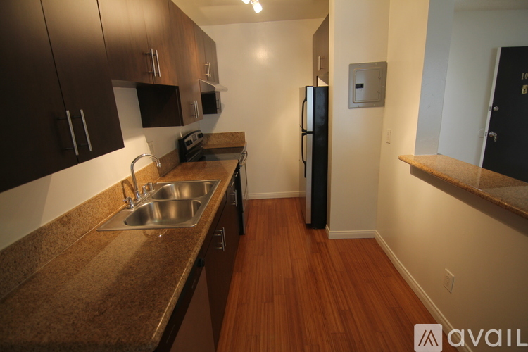 A kitchen with brown cabinets and a black refrigerator.