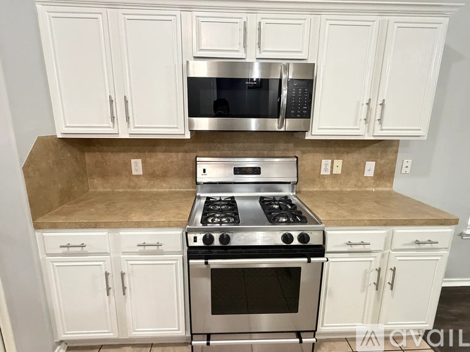 A kitchen with white cabinets and a stainless steel stove and microwave.