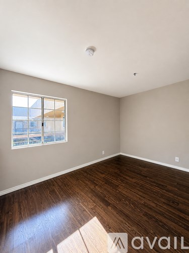 A room with wooden floors and a window overlooking a building.