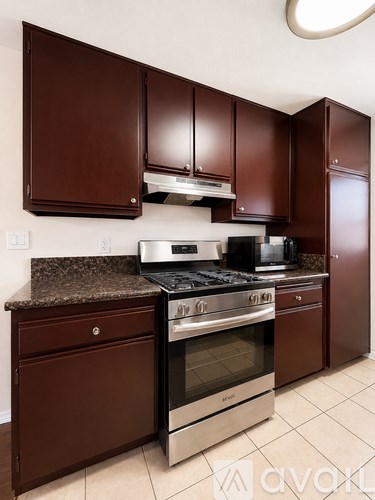 A kitchen with brown cabinets and a stainless steel oven.