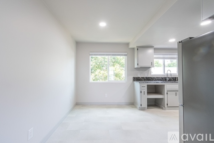 A kitchen area with a refrigerator, sink, and cabinets.