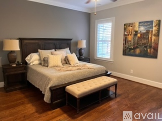 A bedroom with a large bed and a painting on the wall.