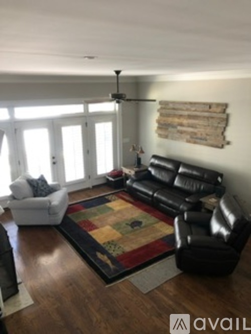 A living room with a black leather couch and a white chair.
