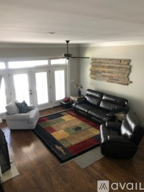 A living room with a black leather couch and a white chair.