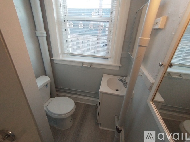 A bathroom with a toilet, sink, and window.